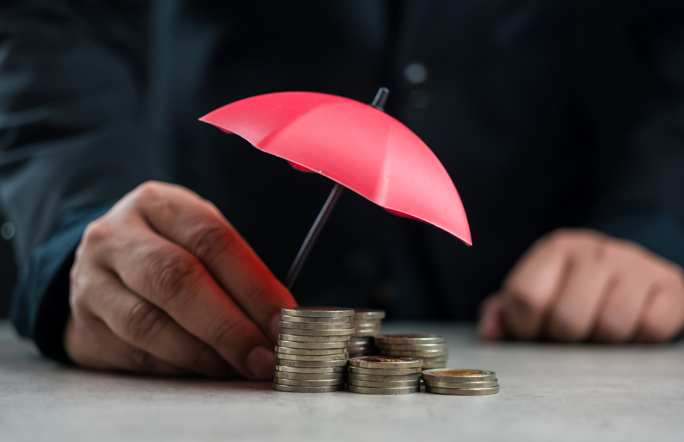 holding umbrella over pile of coins